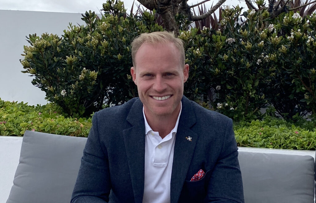 Joe Shew seated outdoors in a navy suit