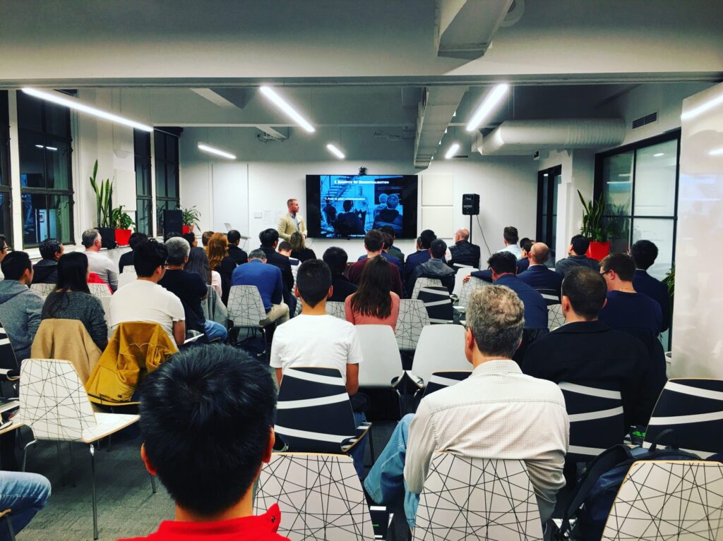 A seated audience facing a presentation screen in a conference room