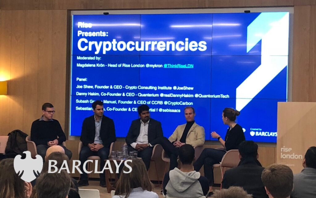 A panel discussion on cryptocurrencies in front of a Barclays backdrop