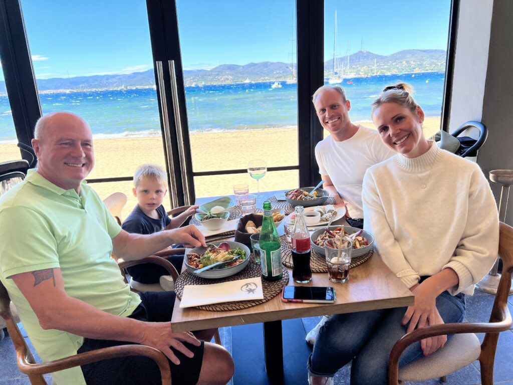 A group sharing a meal at a table overlooking the sea