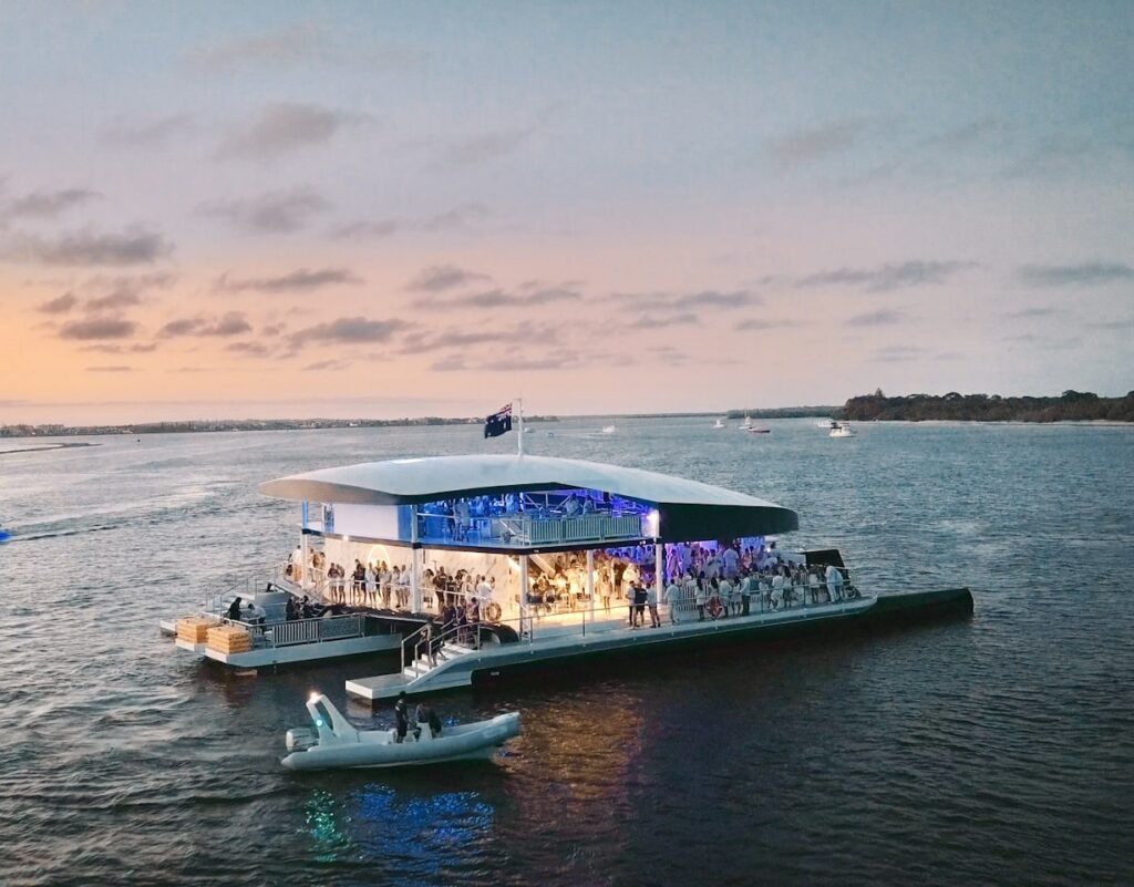 A party boat lit up on the water at sunset