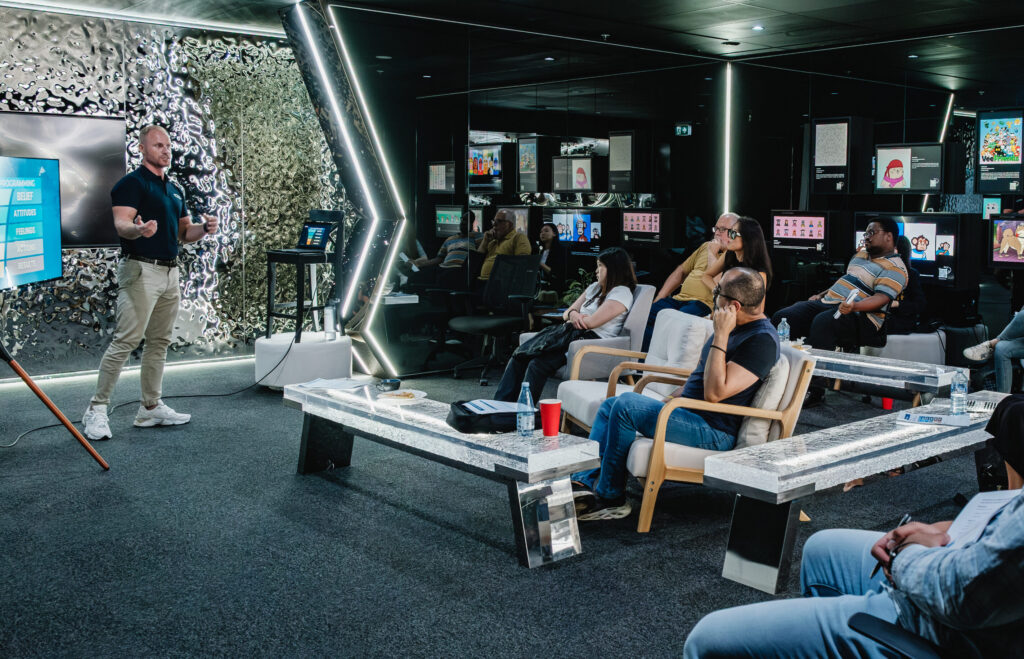 An audience seated in a dark event space facing a stage